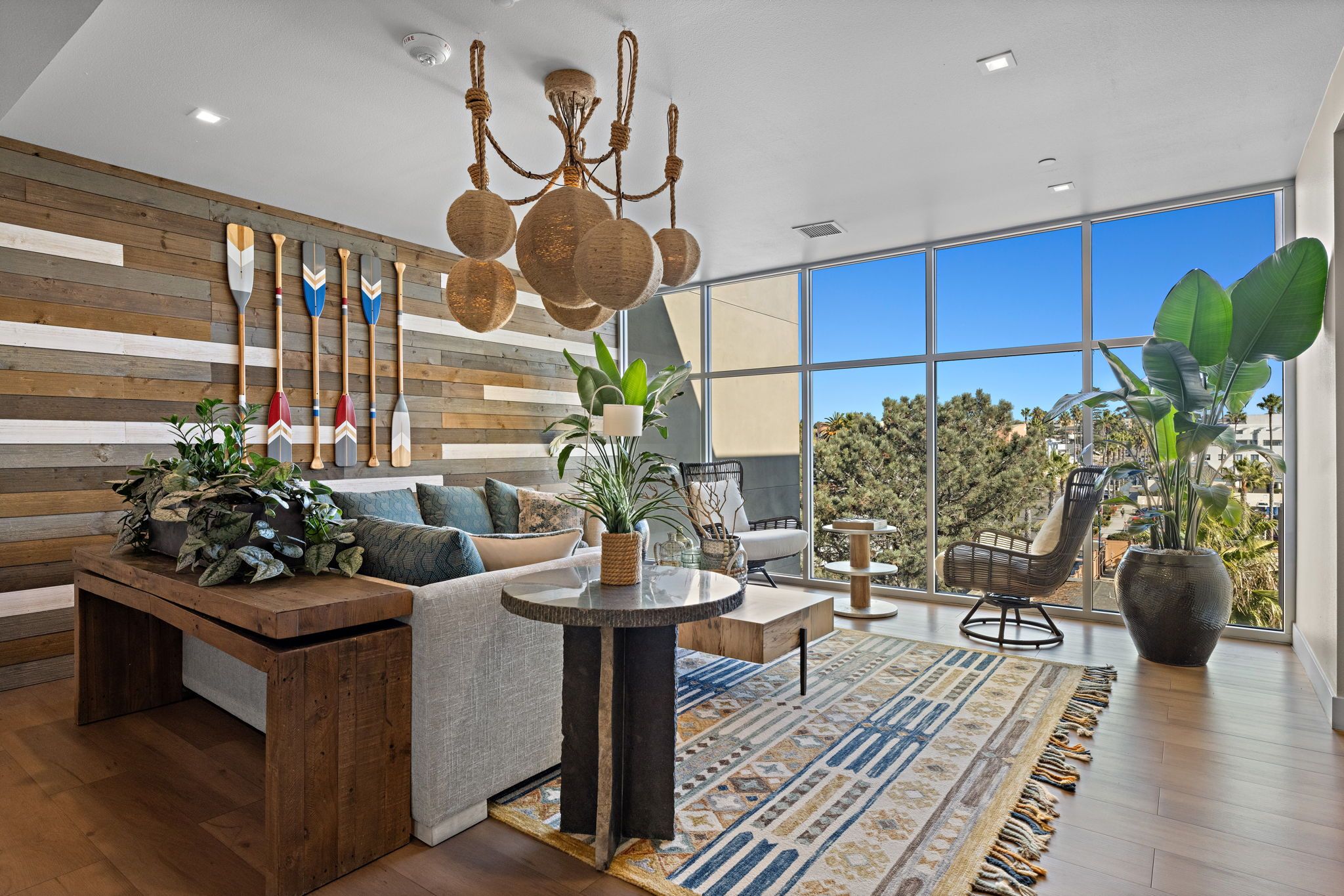 A modern living room with a wooden wall, a large window, and a view of trees.