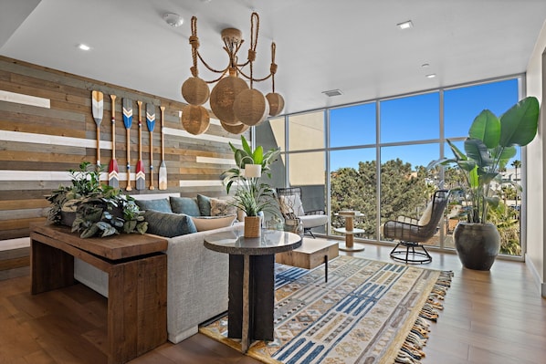 A modern living room with a wooden wall, a large window, and a view of trees.