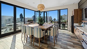 Une cuisine moderne avec de grandes fenêtres, un coin repas avec des chaises à rayures et une vue sur la ville.