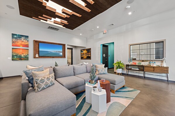 A modern living room with a sectional sofa, a coffee table, and artwork on the walls.