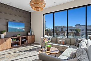 A modern living room with a large window, a television, and a sofa.