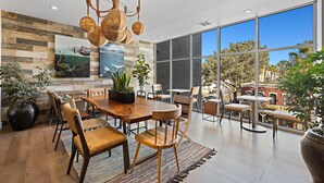 Un vaste espace dédié à la salle à manger, avec une grande table et des chaises en bois, le tout entouré de grandes fenêtres offrant une vue sur la ville.