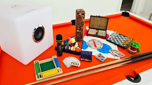 A pool table with various games and objects, including a speaker, dice, playing cards, and a toy crocodile. - STARLAND Luxury Pool Villa Pattaya Walking Street (Pattaya)