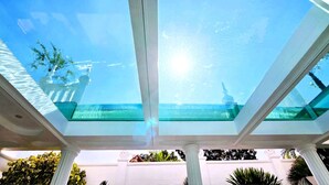 A modern building with a glass ceiling overlooking a body of water.
