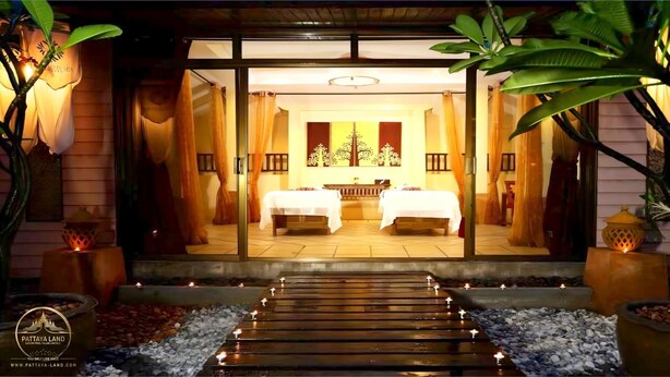 A hotel entrance with a pathway leading to a room with two beds, a reception area, and tropical plants.