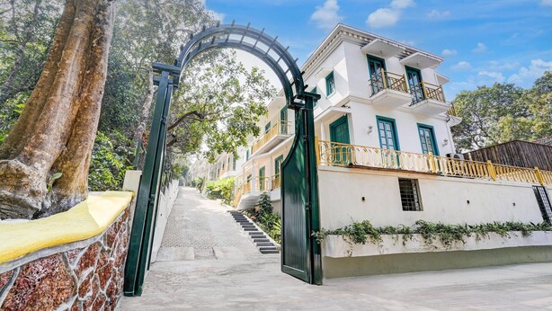 A building with a white facade, green window frames, and a balcony with a yellow railing. - Villa in Siolim Near Morjim Beach (Siolim)