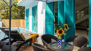 A patio area with wicker furniture, a glass table, and a striped umbrella. - Villa in Siolim Near Morjim Beach (Siolim)