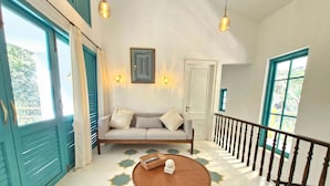 A spacious living area with a sofa, a coffee table, and a staircase. - Villa in Siolim Near Morjim Beach (Siolim)