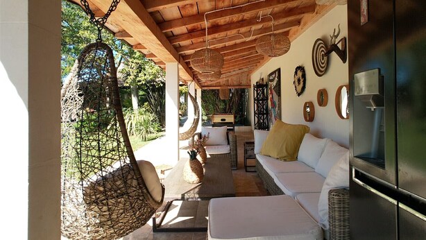 A cozy outdoor seating area with a hanging chair, a sofa, and a water dispenser.