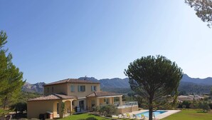 A two-story house with a swimming pool, surrounded by a grassy area and trees. - Holiday rental villa view and pool AUREILLE LS1-449 (Aureille)