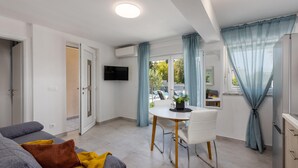 Een moderne woonkamer met een bank, een eettafel en een televisie.