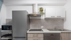 Een moderne keuken met een ingebouwde magnetron, een roestvrijstalen koelkast en een vaatwasser.