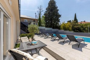 Ein Poolbereich mit Liegestühlen, einem Tisch mit einem Getränk und Blick auf den Pool.