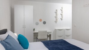 Een slaapkamer met een bed, een bureau en een kledingkast.