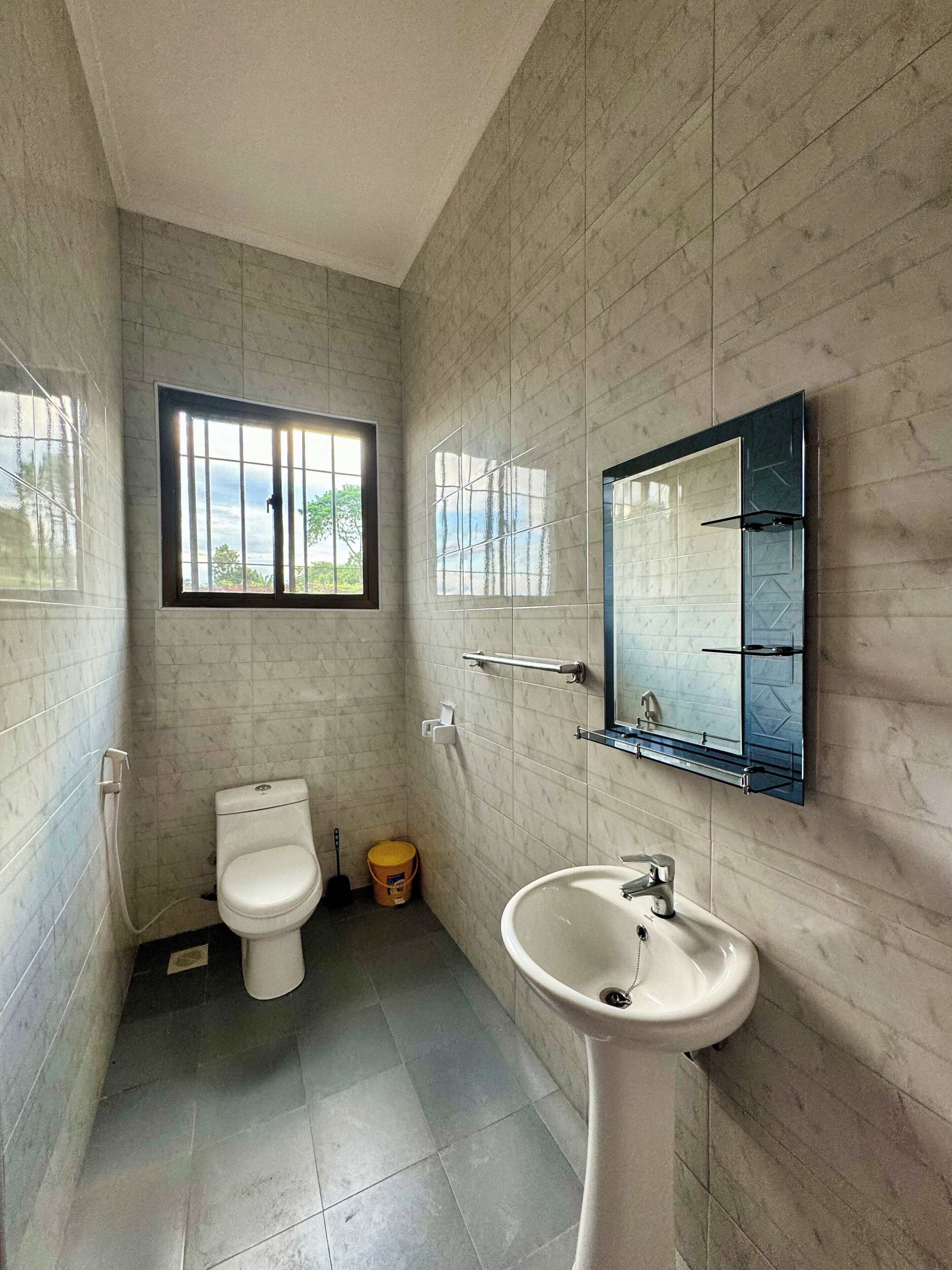 A small bathroom with a toilet, sink, and window.