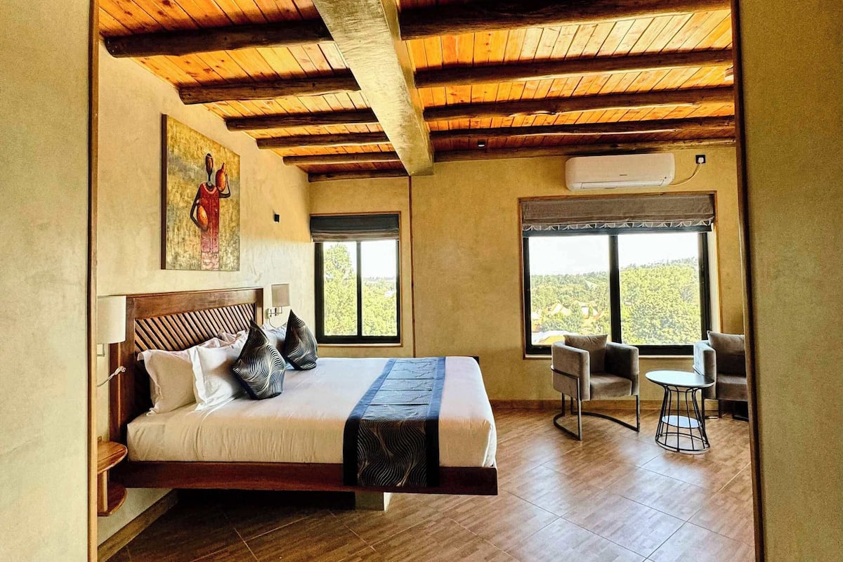 A spacious room with a large bed, a small table, and a window with a view.