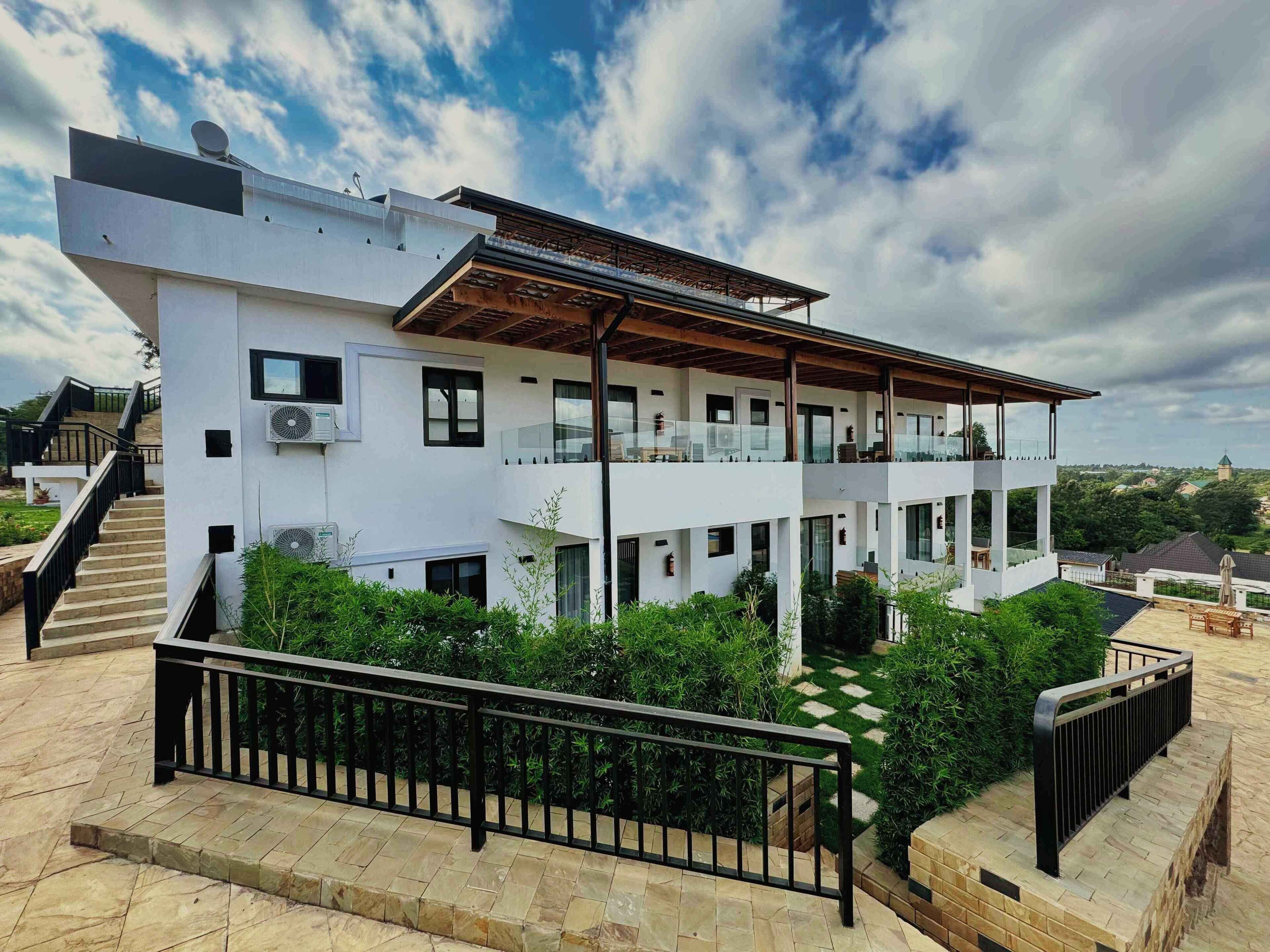A modern two-story building with a flat roof, large windows, and a balcony.