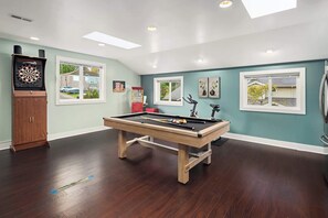 A pool table in a room with teal walls, a dartboard, and a jukebox. - Serene Waterfront Escape w, Amazing View & Hot Tub (Lynnwood)