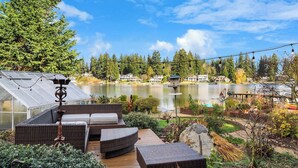 A patio with wicker furniture, a greenhouse, and a lake view.