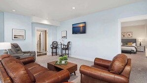 A living room with leather sofas, a coffee table, and a TV mounted on the wall.