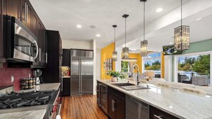 A modern kitchen with a central island, stainless steel appliances, and pendant lighting.