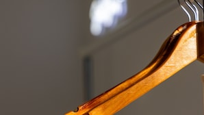 Un cintre en bois muni d’un crochet en métal.