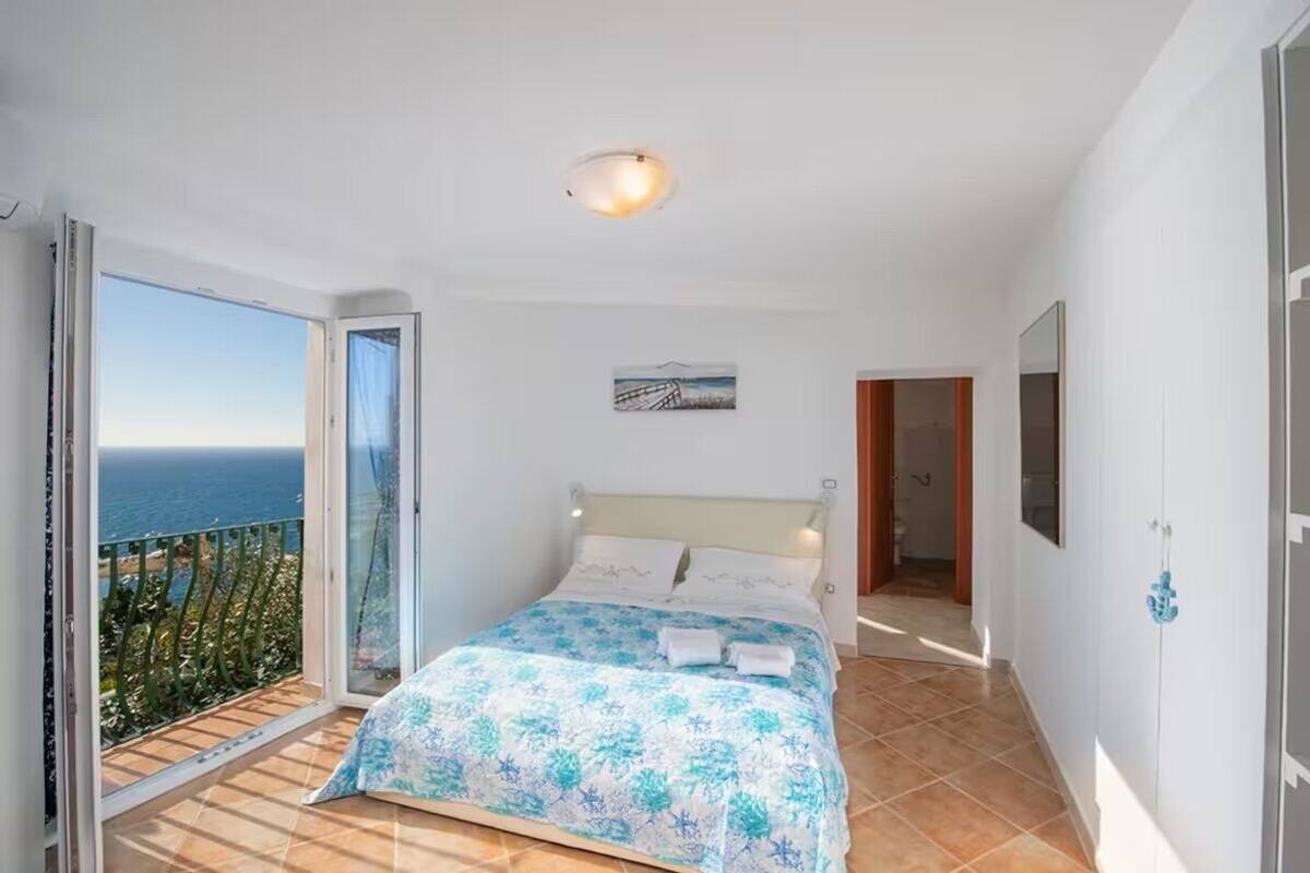 Une chambre avec un lit, une vue sur la mer et un balcon.
