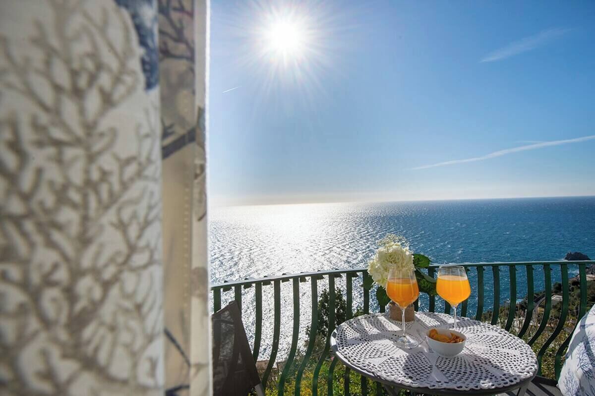 A balcony with a table set for two, overlooking a coastal view.