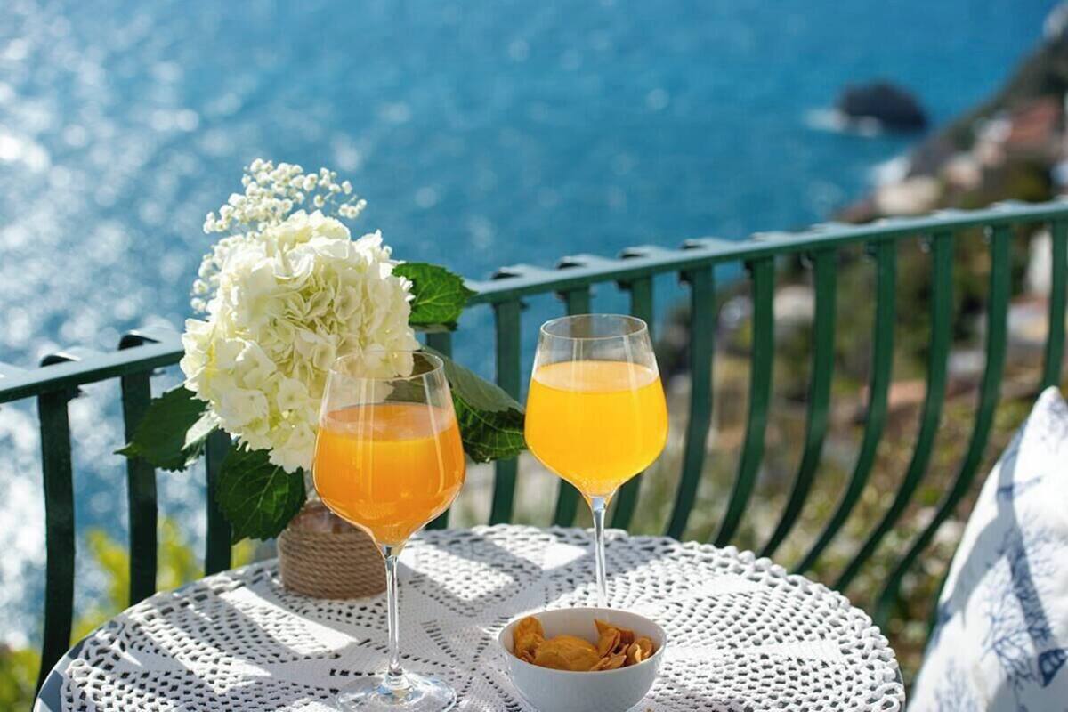 Une table avec des boissons et un bol de collations sur un balcon donnant sur la mer.
