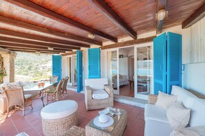 Relax in this serene outdoor space with a glass table, wicker furniture, and a white sofa.