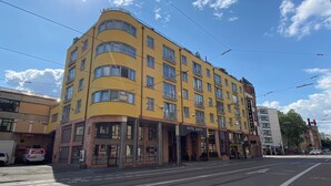 Un immeuble jaune à plusieurs étages, sur lequel on peut lire l’inscription « HÔTEL SANTO ».