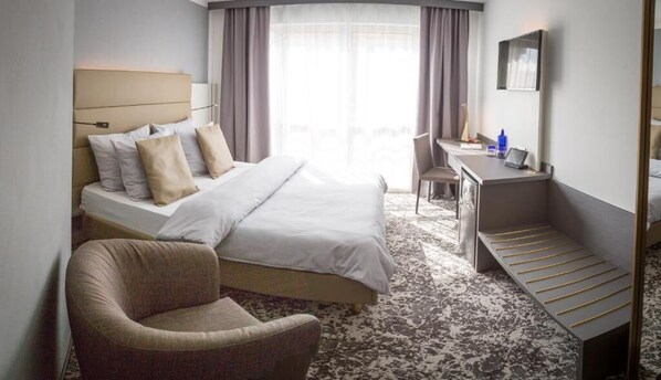 Una habitación de hotel con una cama, un escritorio, una silla y una mesita.