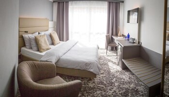 Una habitación de hotel con una cama, un escritorio, una silla y una mesita.