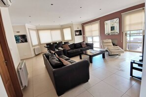 Relax in this stylish living space with a black leather sofa, cream-colored armchair, and dining area.