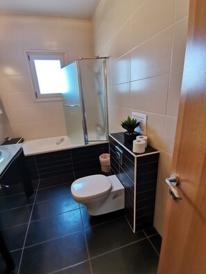 Bathroom features a toilet, glass shower enclosure, and a sink with a mirror above.
