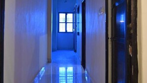 A hallway with a reflective floor, doors on both sides, and a window at the end.