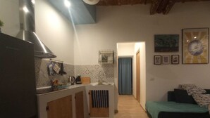 A compact kitchen with a central island, a dining area, and a sofa. - Palermhost (Palermo)