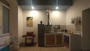 A compact kitchen with a central island, a hanging light fixture, and a wall-mounted dish rack. - Palermhost (Palermo)