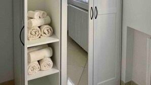 A white wardrobe with two doors and a shelf, containing rolled towels.
