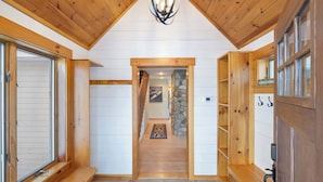 A wooden interior with a stone wall, wooden benches, and a stone floor leading to a hallway. - Family Retreat | 10 Min to Okemo (Ludlow)