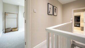 A hallway with a white railing, a coat rack, and a basket. - Stylish Flat, short walk to town (Oxford)