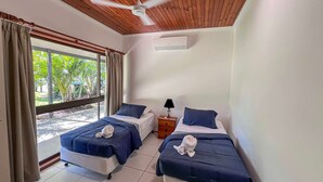 A room with two beds, a ceiling fan, a nightstand, and a window with curtains. - Bluefin House beachfront access (Mission Beach)