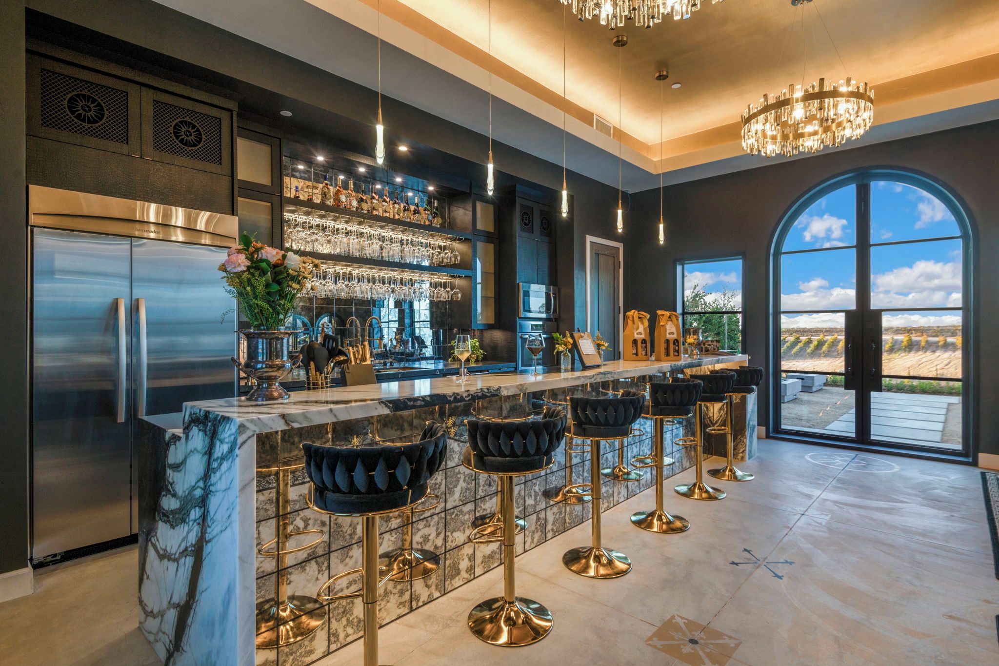 A modern kitchen with a marble countertop, stainless steel appliances, and a bar area with bar stools.