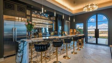 A modern kitchen with a marble countertop, stainless steel appliances, and a bar area with bar stools.