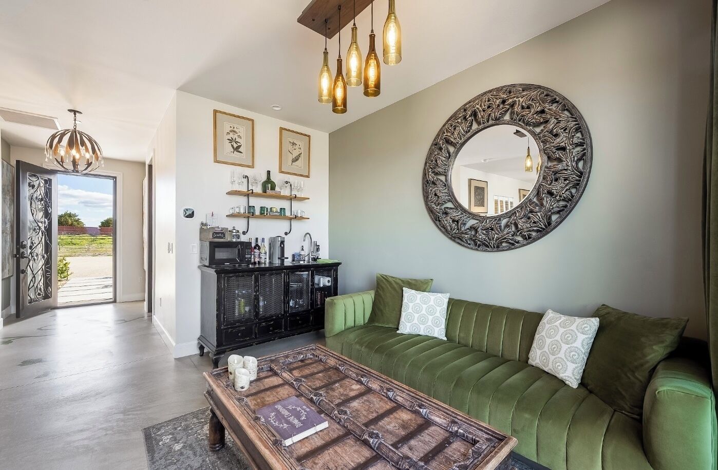 A modern living room with a green sofa, a coffee table, and a decorative mirror.