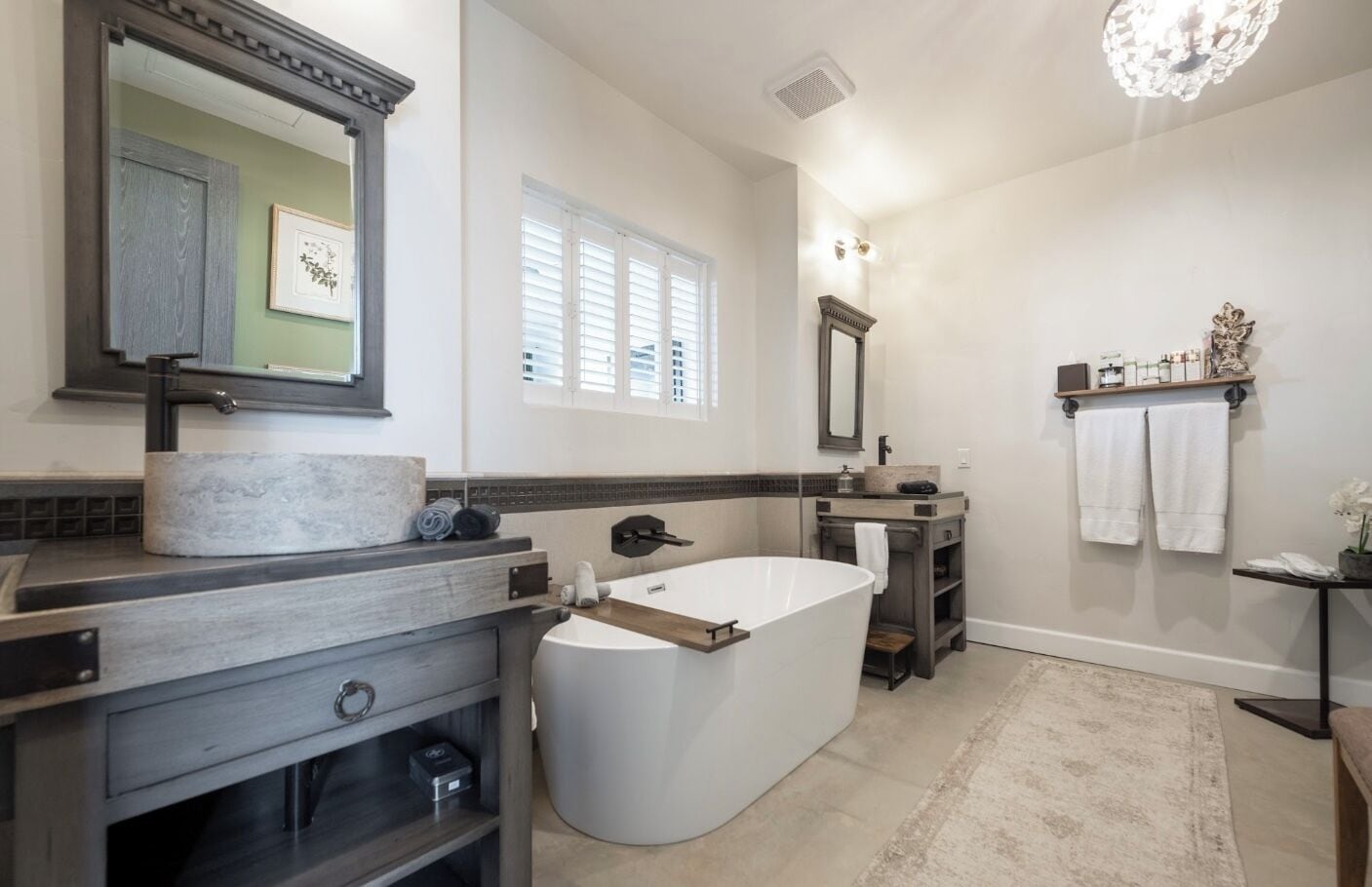 A modern bathroom with a freestanding bathtub, a large mirror, and a vanity with a marble countertop.