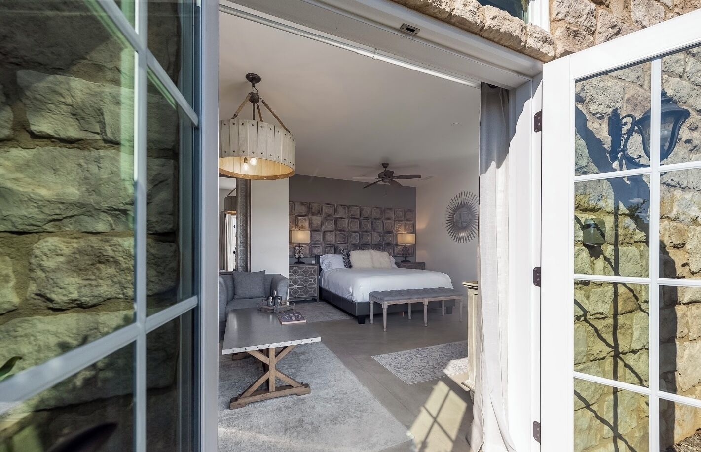 Een moderne slaapkamer met een bed, een bank, een salontafel en een plafondventilator.