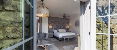 Een moderne slaapkamer met een bed, een bank, een salontafel en een plafondventilator.