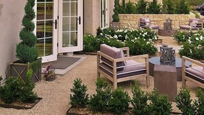 A house with a patio area featuring outdoor furniture and a stone wall. - Domaine Chardonnay (Temecula)
