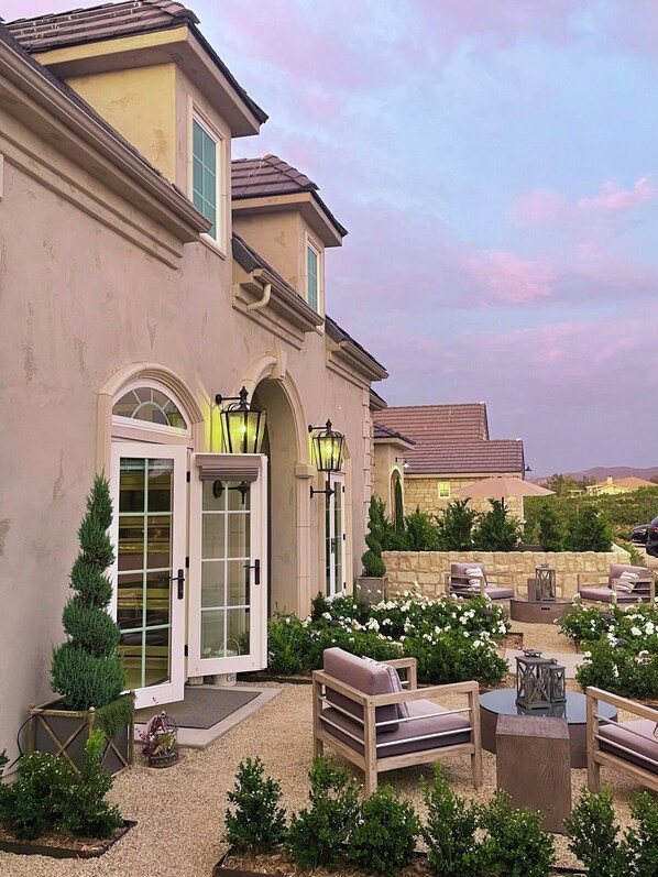 A house with a patio area featuring outdoor furniture and a stone wall. - Domaine Chardonnay (Temecula)